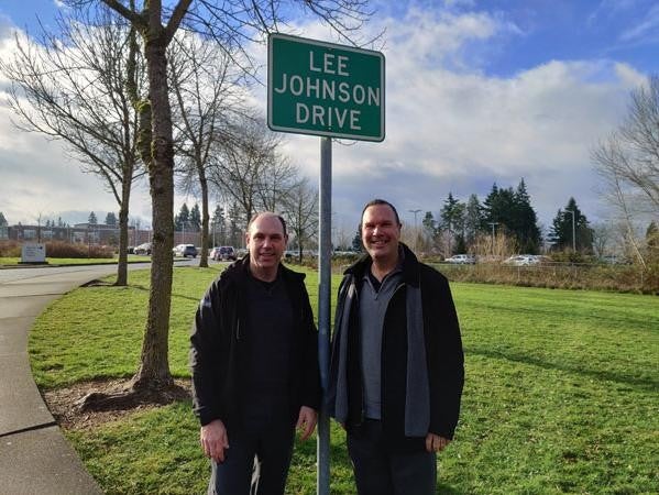 Two men standing in front of a street sign